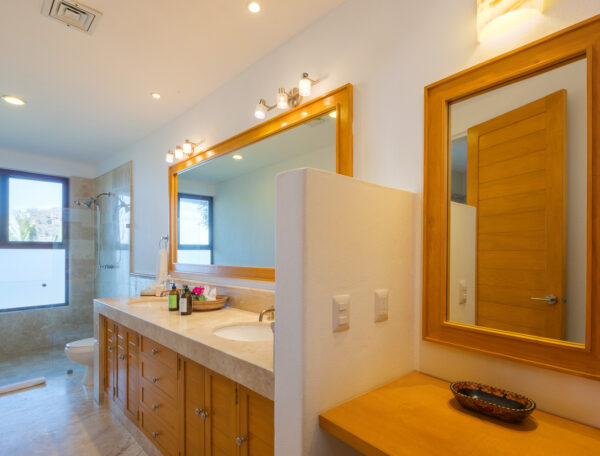 Villa Magnifico Modern bathroom in Mismaloya villa: large mirror, twin sinks, marble countertop; natural light and warm ambiance.