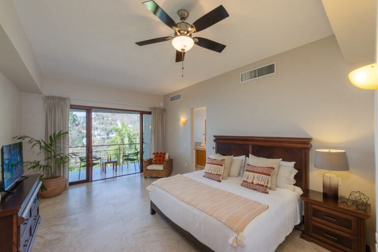Villa Magnifico Luxurious bedroom in Mismaloya, near Puerto Vallarta, features a large bed, balcony with scenic greenery views.
