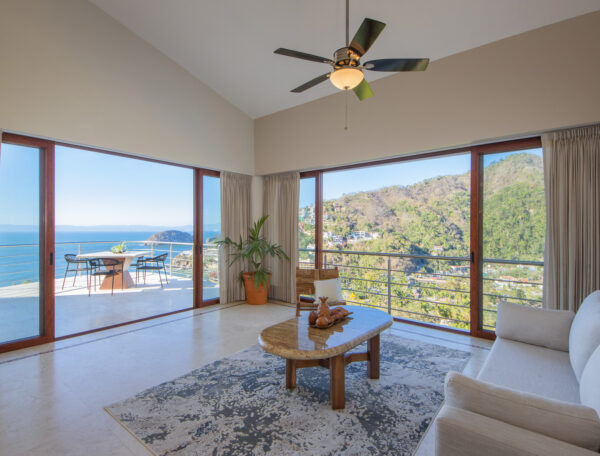 Villa Magnifico Luxurious Mismaloya Villa living room, near Puerto Vallarta, Mexico, with ocean views, beige sofa, and balcony access.