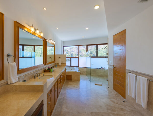 Villa Magnifico Mismaloya, near Puerto Vallarta: Spacious bathroom with double sink, glass shower, bathtub by windows; well-lit with ceiling lights.