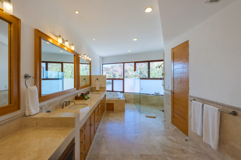 Villa Magnifico Mismaloya, near Puerto Vallarta: Spacious bathroom with double sink, glass shower, bathtub by windows; well-lit with ceiling lights.