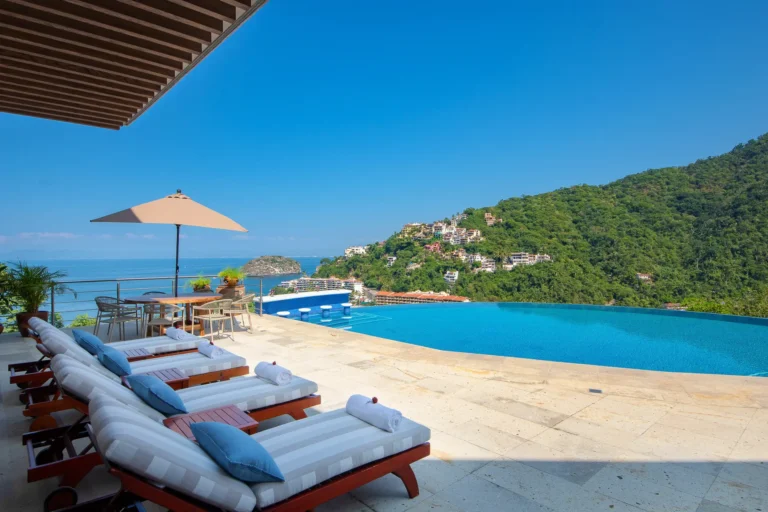 Villa Magnifico Luxury outdoor poolside area with loungers in Mismaloya, near Puerto Vallarta, Mexico. Infinity pool overlooks ocean.