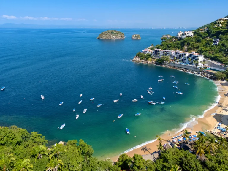 Villa Magnifico Aerial view of tranquil Mismaloya beach cove near Puerto Vallarta, Mexico, with boats and lush hillside villas.