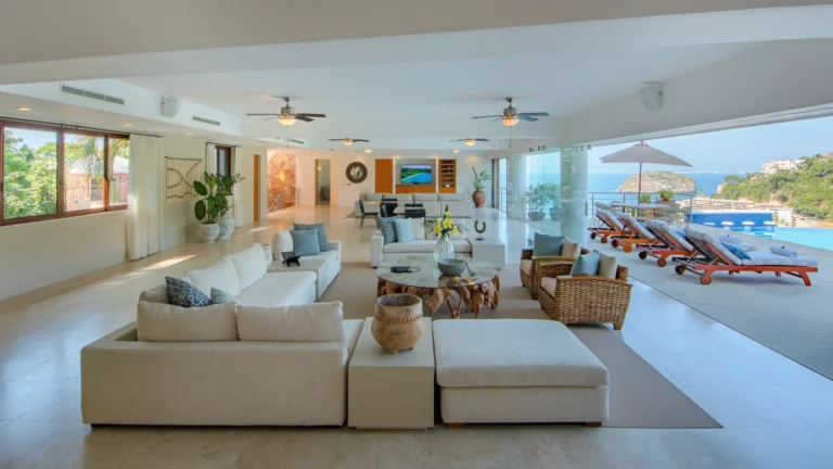 Villa Magnifico Open-plan living area with white sofas, wooden table; terrace in Mismaloya, near Puerto Vallarta boasts ocean view.
