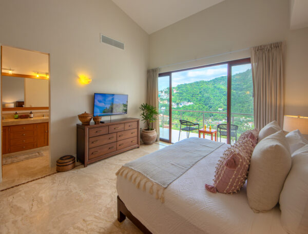 Villa Magnifico Luxury Villa in Mismaloya: Bedroom with large bed, TV, balcony view of lush hills near Puerto Vallarta, Mexico.