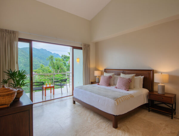 Villa Magnifico Bedroom in a Mismaloya villa near Puerto Vallarta, Mexico, featuring mountain views from a balcony with chairs.