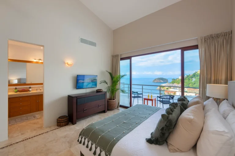 Villa Magnifico Large ocean-view bedroom in luxury Mismaloya villa near Puerto Vallarta, Mexico; balcony with chairs, dresser, plants.