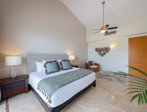 Villa Magnifico Elegant bedroom with high ceiling, green accents, and potted plant in luxurious Mismaloya Villa near Puerto Vallarta, Mexico.