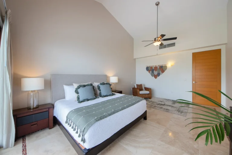 Villa Magnifico Spacious bedroom with a large bed, green accents, ceiling fan, and cozy sitting area in Mismaloya Villa, near Puerto Vallarta.