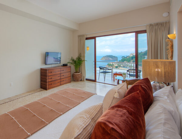 Villa Magnifico Luxury Mismaloya, near Puerto Vallarta: Bedroom with large bed, wooden dresser, TV; balcony views ocean and lush hillside.