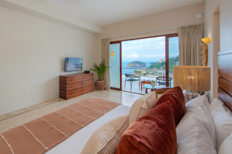 Villa Magnifico Luxury Mismaloya, near Puerto Vallarta: Bedroom with large bed, wooden dresser, TV; balcony views ocean and lush hillside.