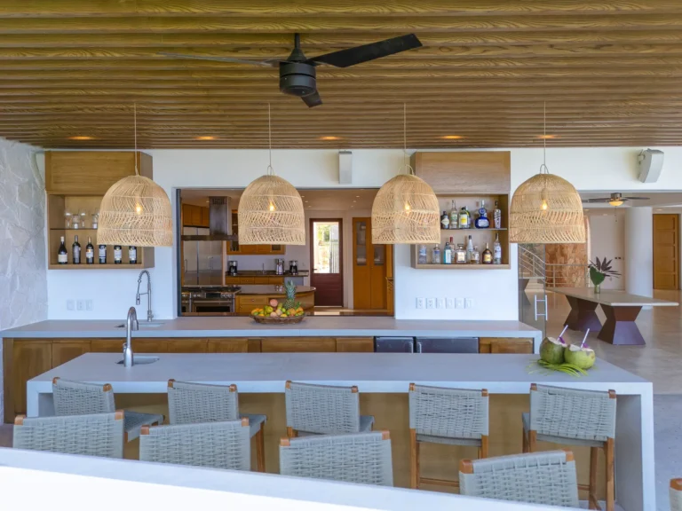 Villa Magnifico A stylish kitchen in a Mismaloya, Puerto Vallarta Villa with wicker lights, wooden accents, and a fruit basket.