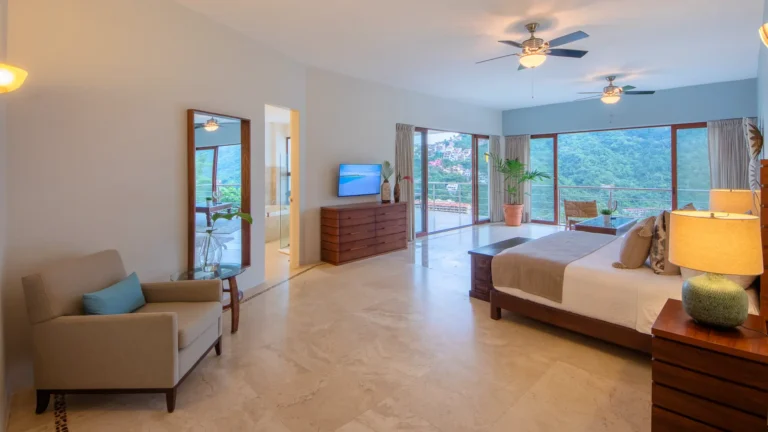 Villa Magnifico Spacious bedroom with large windows, elegant decor, and lush hill views in Mismaloya near Puerto Vallarta, Mexico.