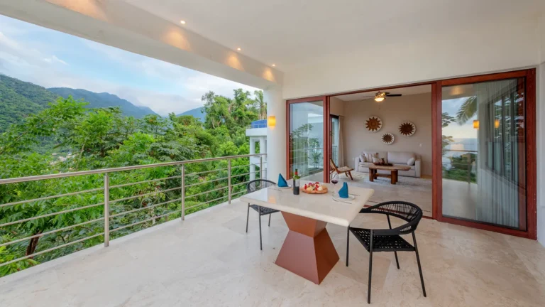 Villa Magnifico Balcony view of lush mountains in Mismaloya, near Puerto Vallarta, Mexico; indoor living area visible.