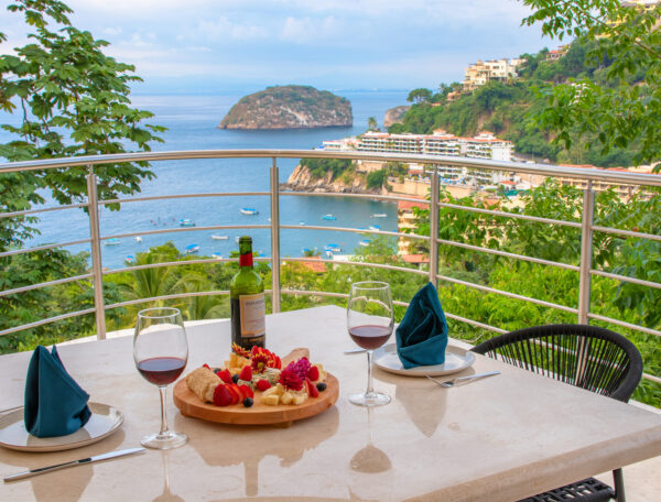 Villa Magnifico Scenic terrace in Mismaloya, near Puerto Vallarta; set table overlooks coastal view with greenery and distant island.