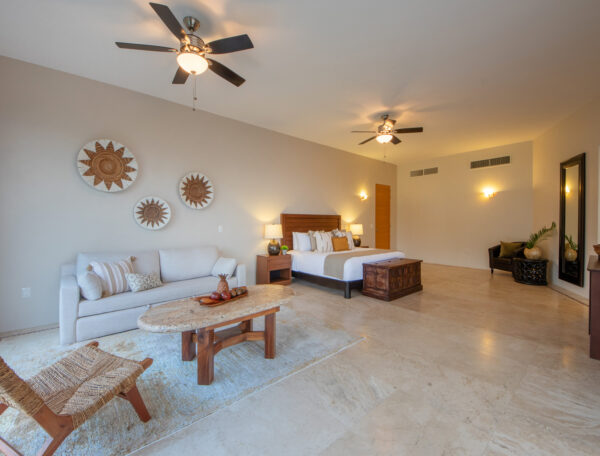 Villa Magnifico Luxury Villa bedroom in Mismaloya, near Puerto Vallarta: king bed, sofa, coffee table, sun wall art, serene ambiance.