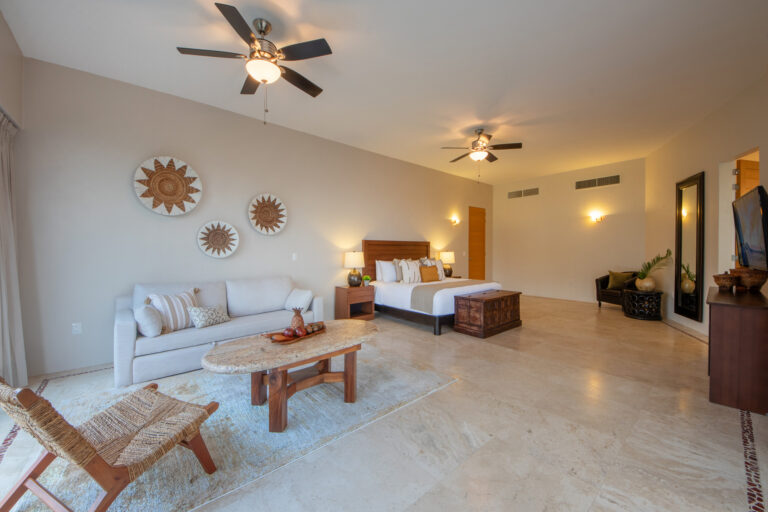 Villa Magnifico Luxury Villa bedroom in Mismaloya, near Puerto Vallarta: king bed, sofa, coffee table, sun wall art, serene ambiance.