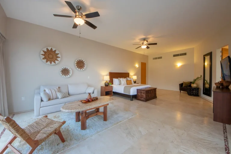 Villa Magnifico Spacious bedroom in Mismaloya villa: large bed, sofa, coffee table; decorated walls; TV on right.