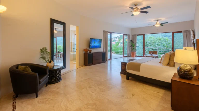 Villa Magnifico Luxury Villa bedroom in Mismaloya, near Puerto Vallarta: large bed, balcony with forest view, modern decor.