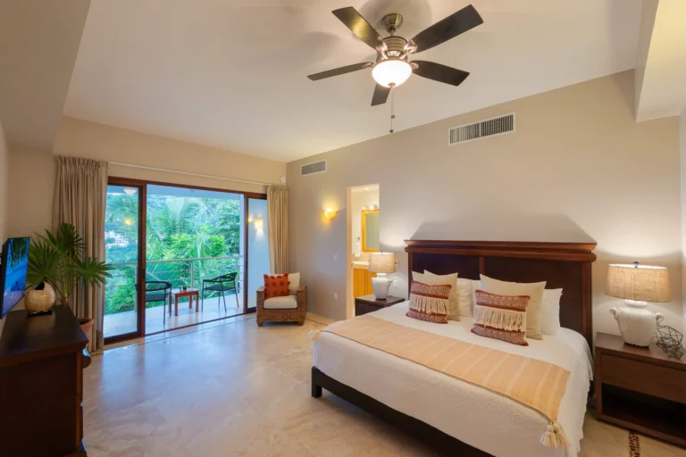 Villa Magnifico Bedroom in Mismaloya luxury villa near Puerto Vallarta features a balcony with outdoor furniture and lush greenery views.