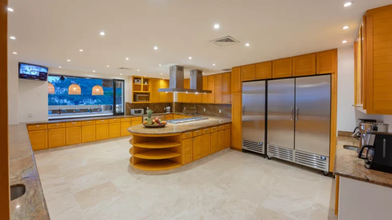 Villa Magnifico Spacious luxury Villa kitchen near Puerto Vallarta, Mexico: wood cabinets, island, stainless refrigerator, view window.