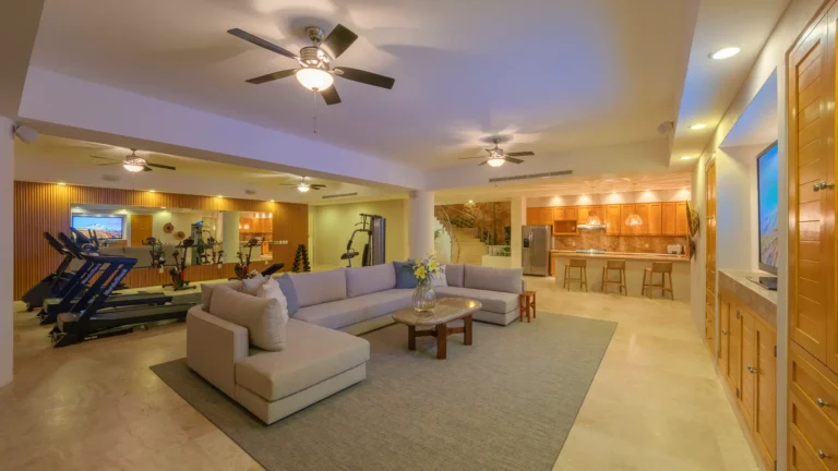 Villa Magnifico Spacious living room with a sectional sofa, home gym, and kitchen. Located in Mismaloya, near Puerto Vallarta.