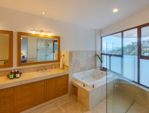 Villa Magnifico Luxurious Villa in Mismaloya: Double sink, tiled jacuzzi, hillside view from windows in bright bathroom near Puerto Vallarta.