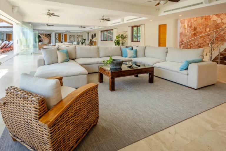 Villa Magnifico Luxury villa in Mismaloya: Spacious living room with a sectional sofa, wooden table, and glass wall to outside.