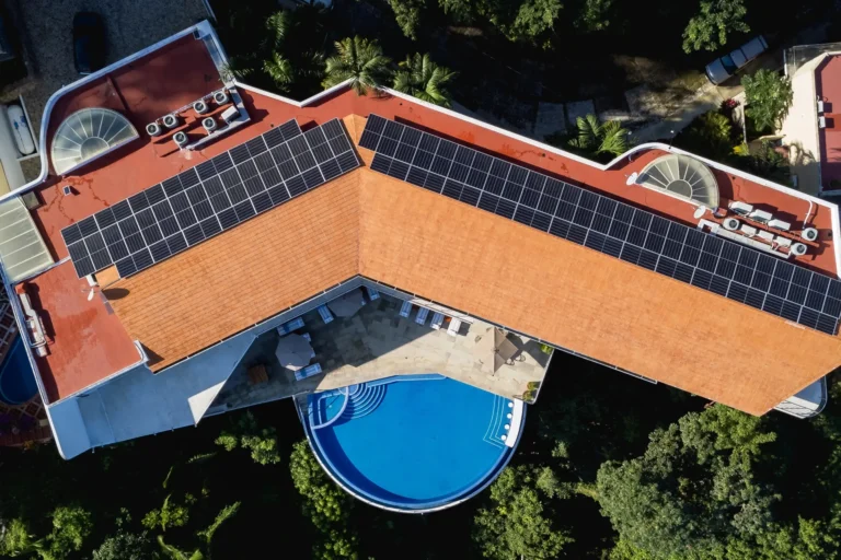 Villa Magnifico Aerial view of Mismaloya luxury villa near Puerto Vallarta: V-shaped terracotta roof with solar panels, curved pool.