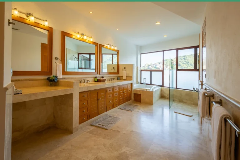 Villa Magnifico Luxurious bathroom in Mismaloya Villa, near Puerto Vallarta: beige marble, dual sinks, wooden cabinet; scenic window view.