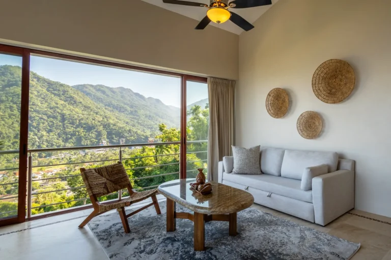 Villa Magnifico Bright living room with mountain view in Mismaloya, Puerto Vallarta; features white sofa, wicker chair, and decor.