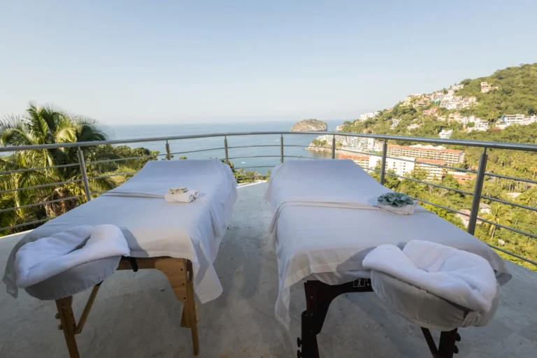 Villa Magnifico Two massage tables on a balcony overlook scenic ocean views and green hills in Mismaloya, near Puerto Vallarta.