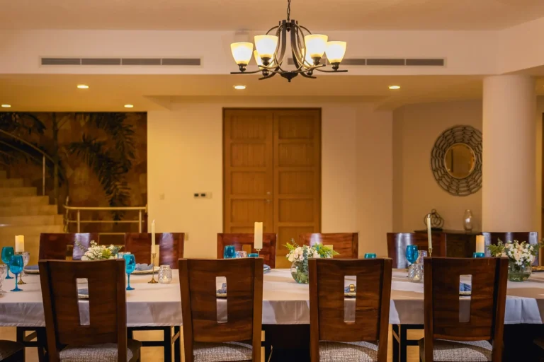 Villa Magnifico Elegant dining room in Mismaloya, near Puerto Vallarta, with a table set with white linens and blue glasses.